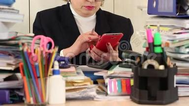 高级女簿记员坐在桌旁，通过智能手机进行交流